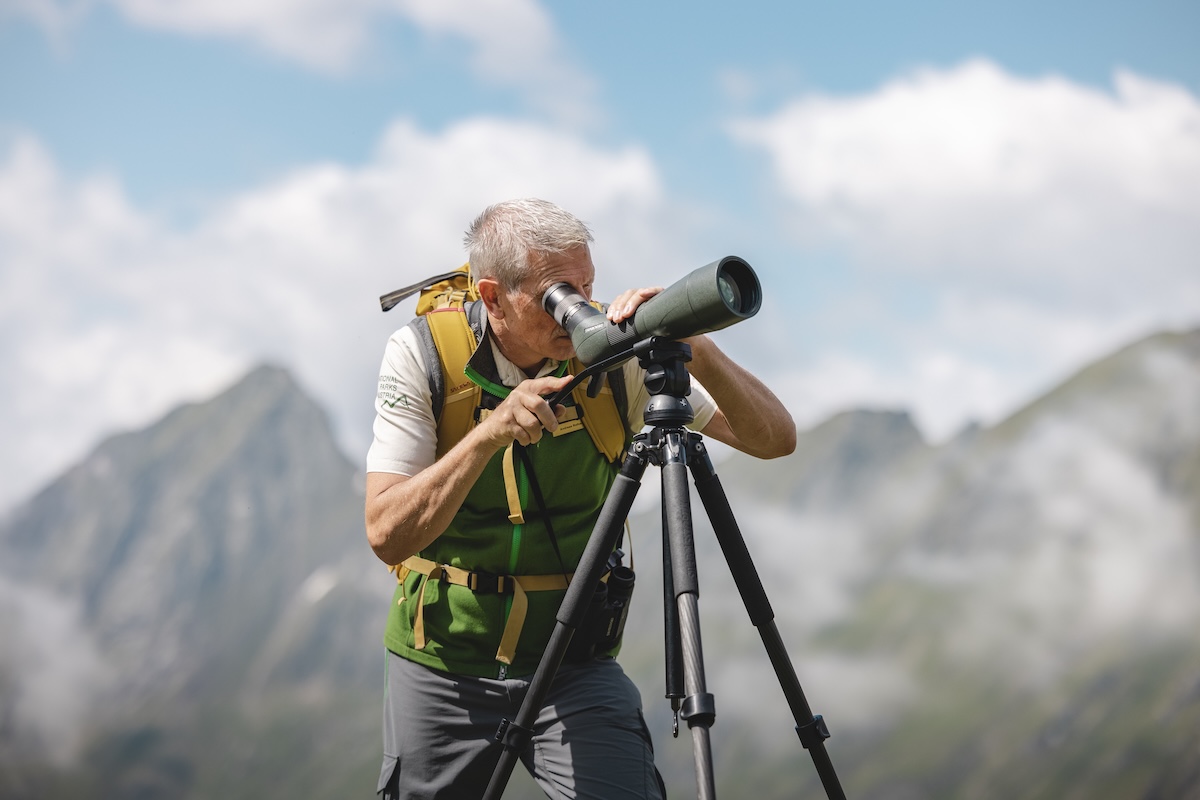 Mann mit Fernrohr in den Bergen